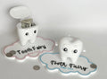 Tooth Fairy Buddy set — pink and blue versions with tooth boxes open showing coins and bills