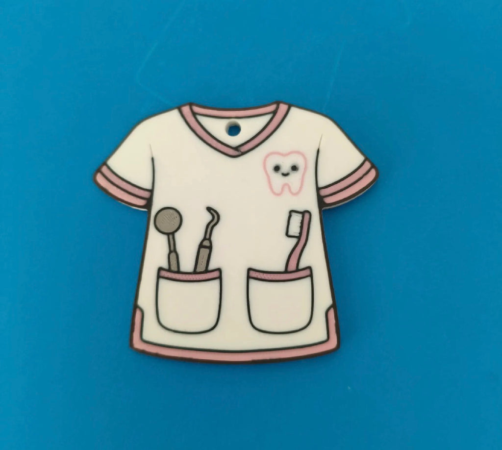 Dental hygienist scrub keychain charm — flat lay on blue background showing tooth logo and tool pockets