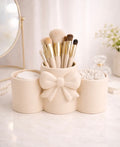 Coquette bow makeup brush holder in cream — styled on marble vanity with brushes and cotton rounds
