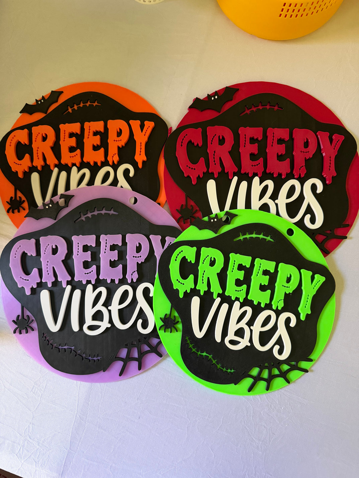 Orange, deep pink, lavender, and green Creepy Vibes round Halloween signs with bat and spiderweb accents