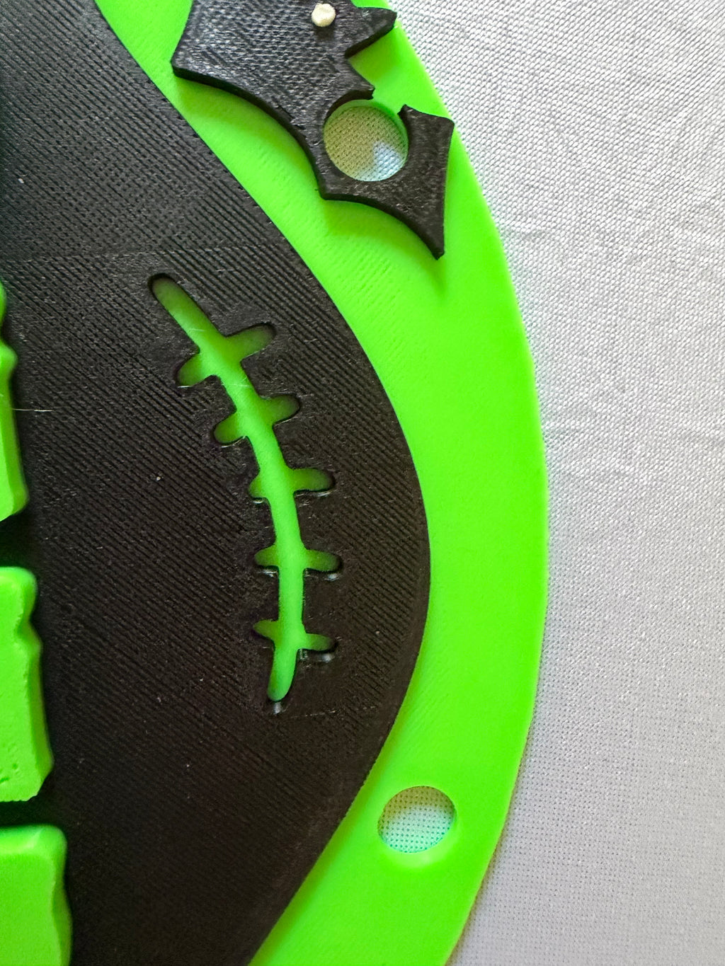 Close-up of green Creepy Vibes sign showing hanging holes, black bat, and stitch detail