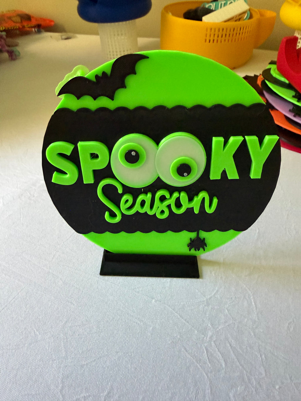 Green Spooky Season round sign displayed upright on a black stand