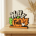 Hello Fall pumpkin and leaves sign on a light wood surface in a warm neutral setting