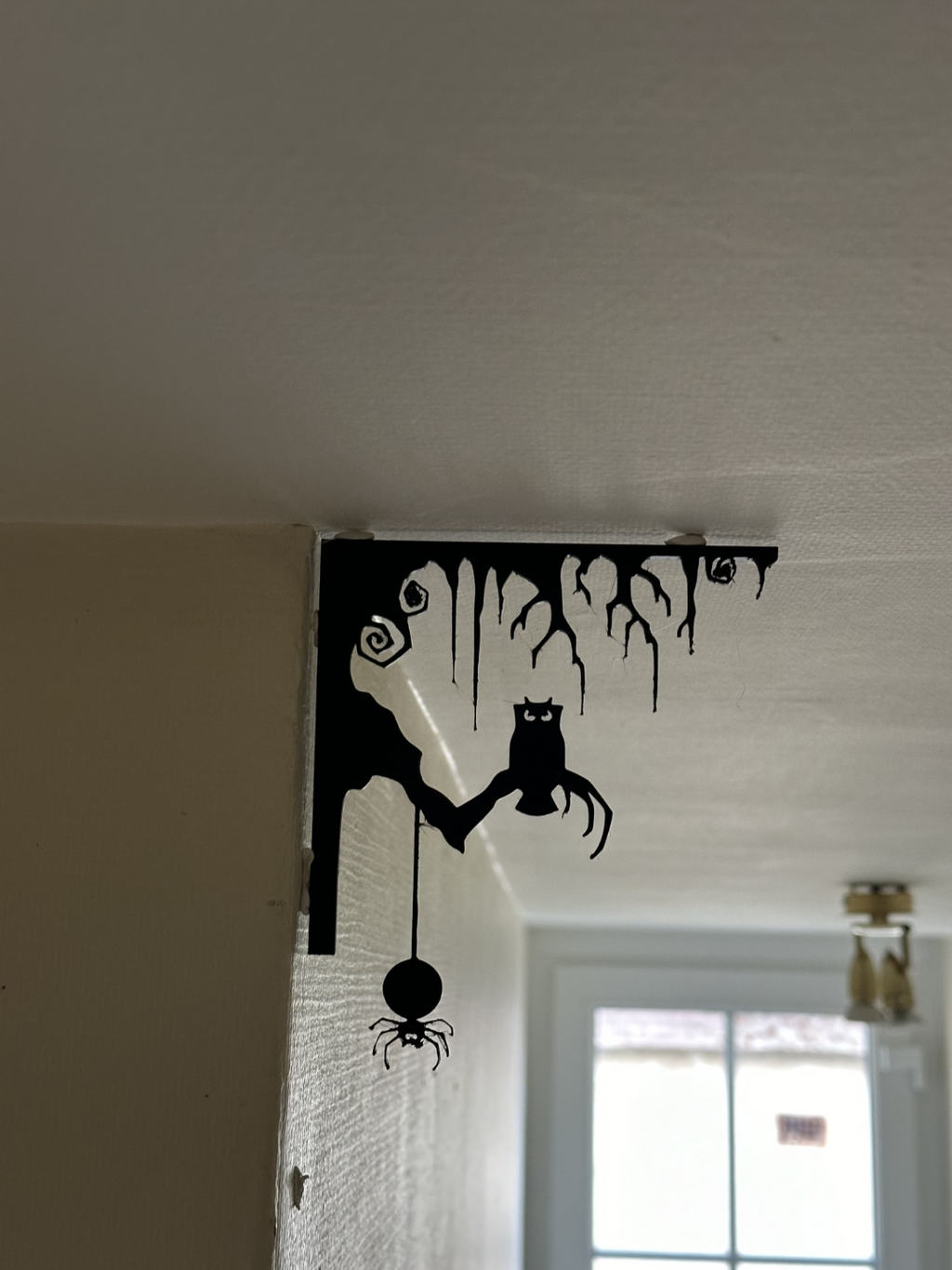 Black Halloween corner wall decoration with owl and dangling spider, angled view showing corner fit