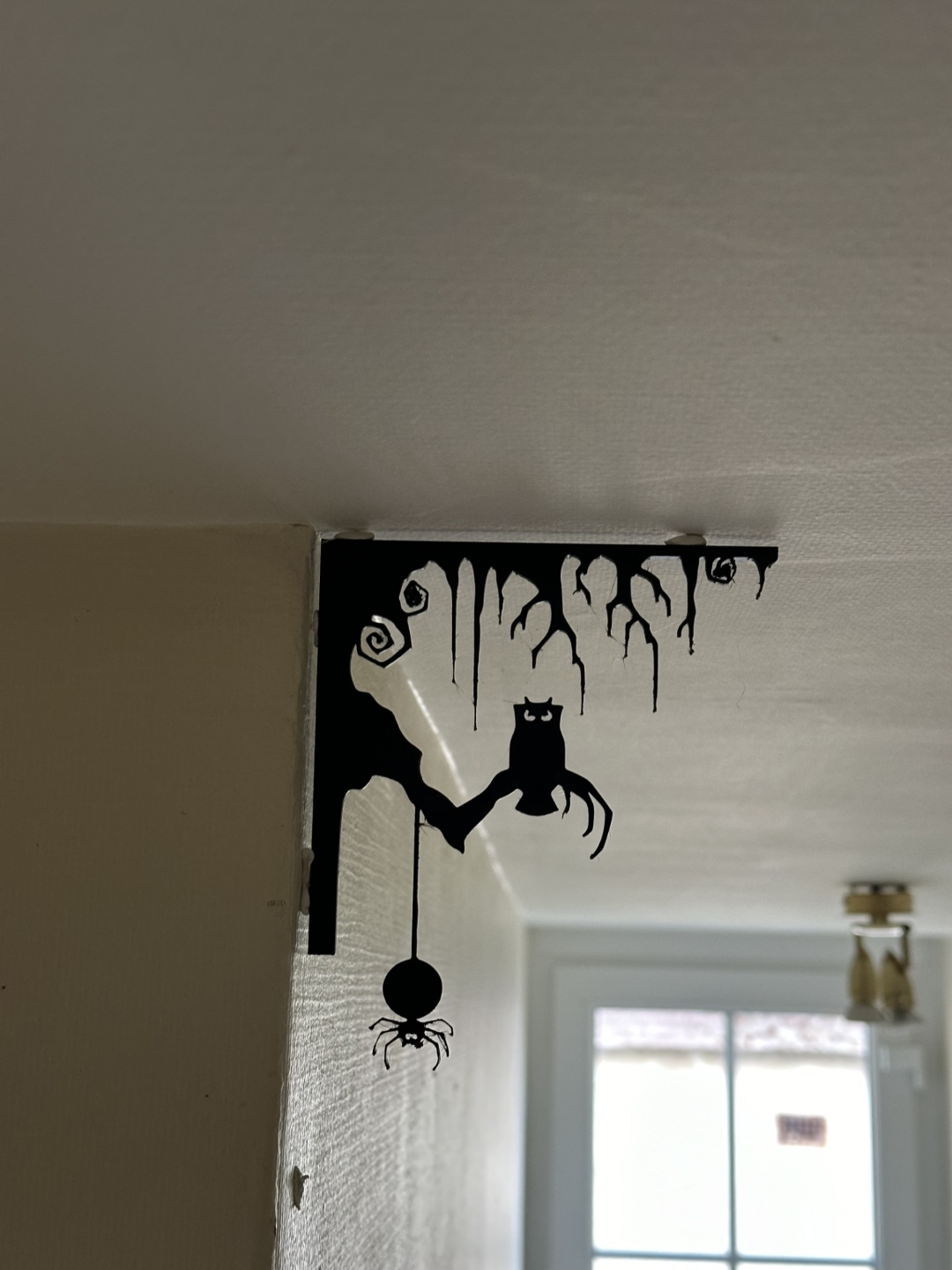 Black Halloween corner wall decoration with owl and dangling spider, angled view showing corner fit