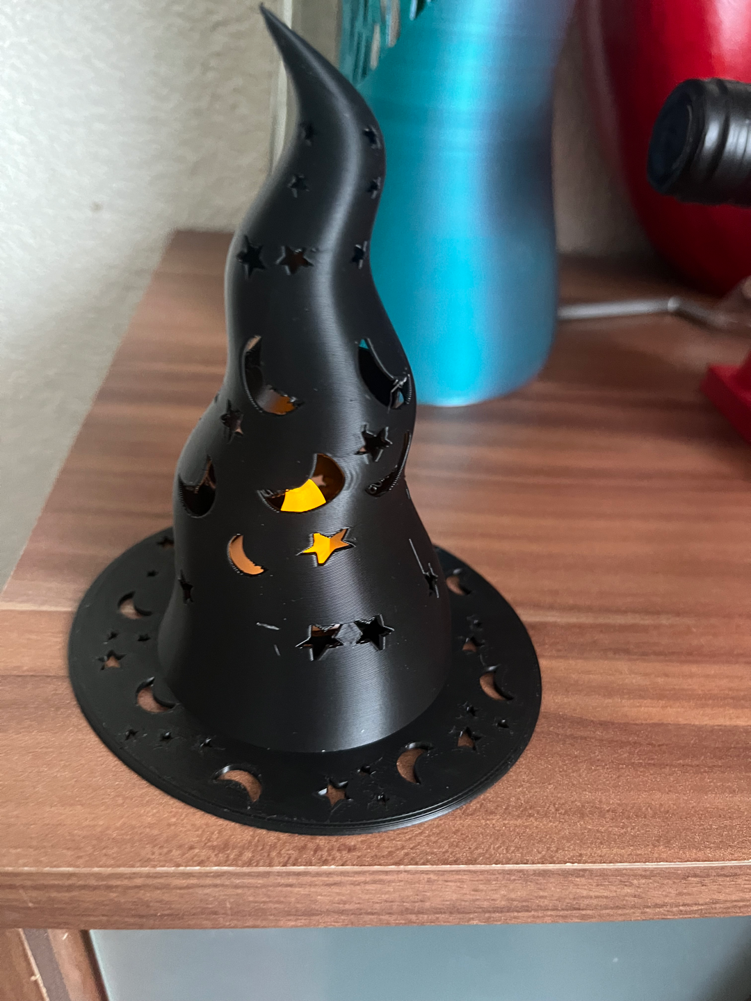Witch hat lantern angled view showing twisted hat shape and celestial cutout pattern with warm glow inside