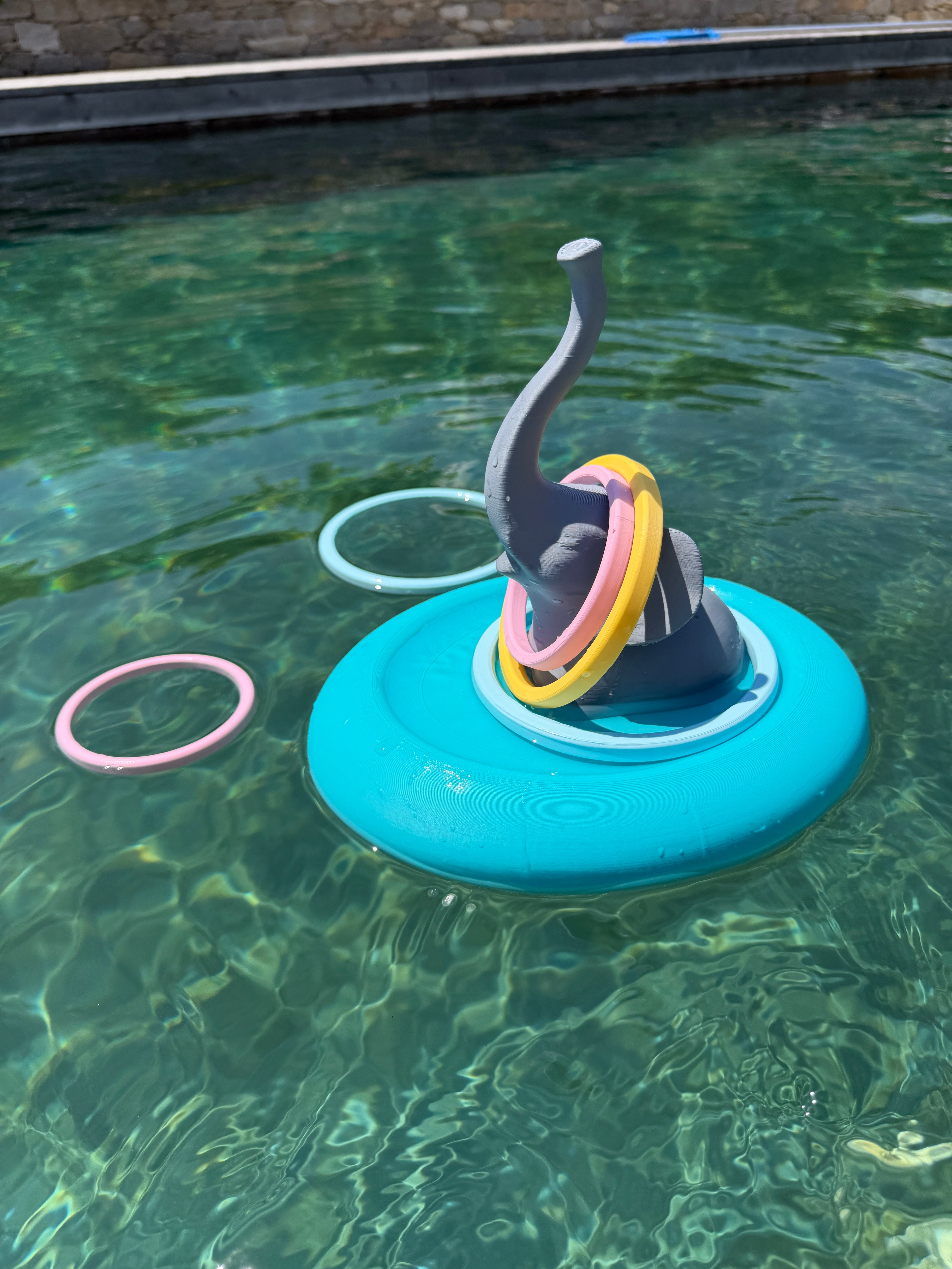 Floating elephant ring toss game in pool with colorful rings around the trunk