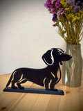 Dachshund silhouette stand on wooden table with flowers