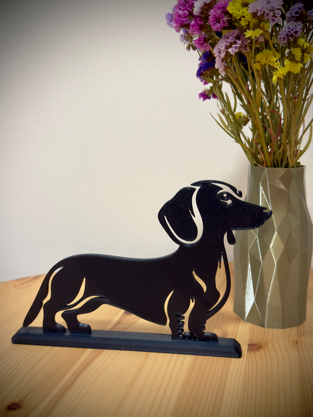 Dachshund silhouette stand on wooden table with flowers