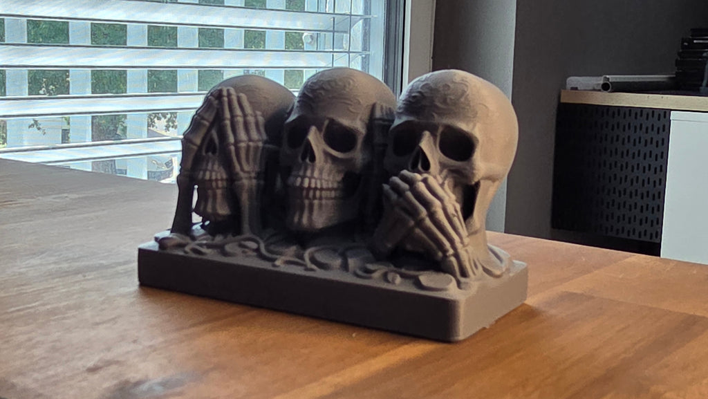 Skull trio figurine angled side view on wooden table by window