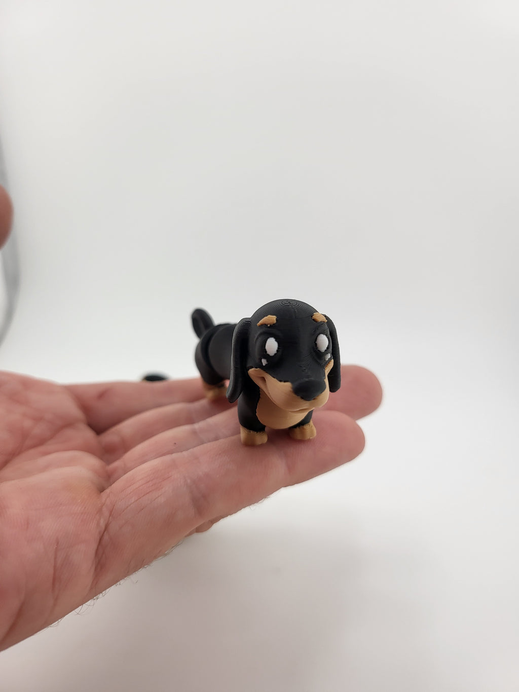 Flexi dachshund keychain held in hand showing size