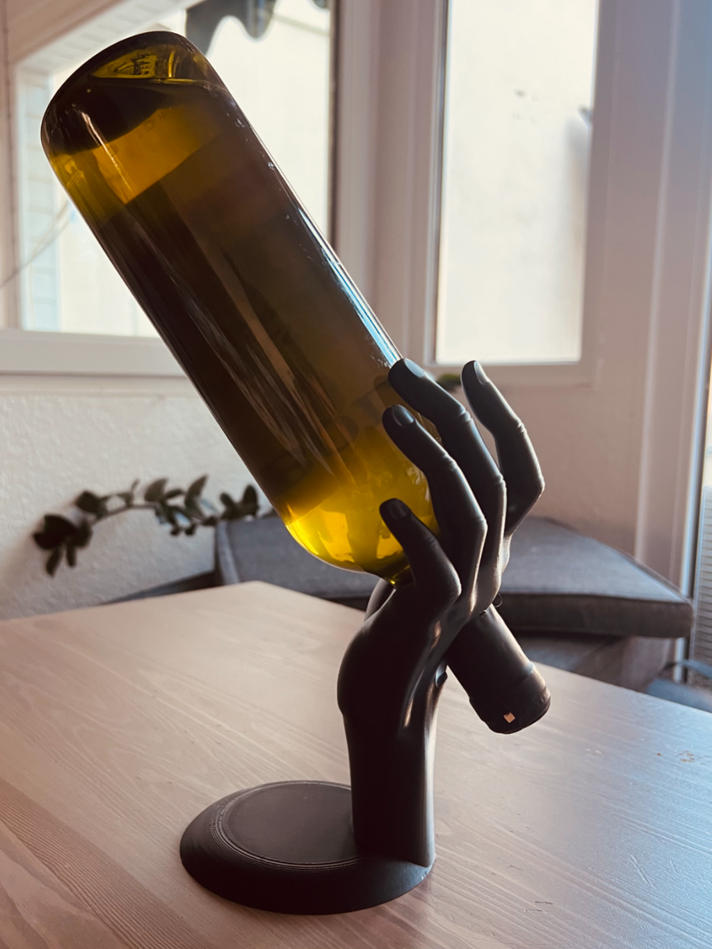 Matte black sculptural hand wine bottle holder holding a white wine bottle, side view