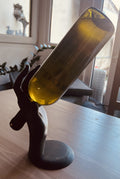 Matte black sculptural hand wine bottle holder holding a white wine bottle at an angle, front view