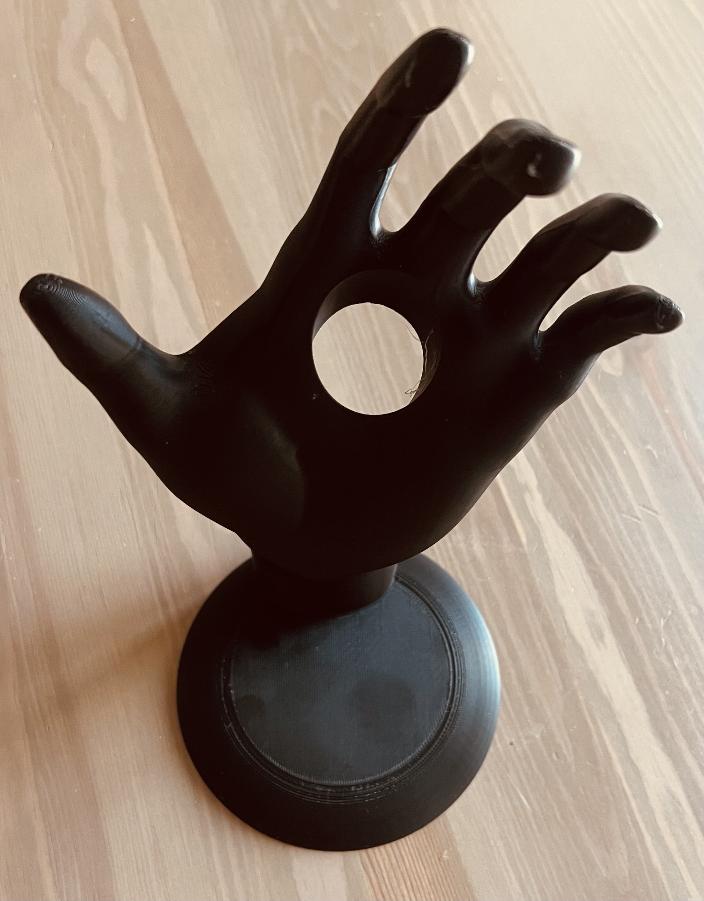 Matte black sculptural hand wine bottle holder empty, showing palm detail and round base