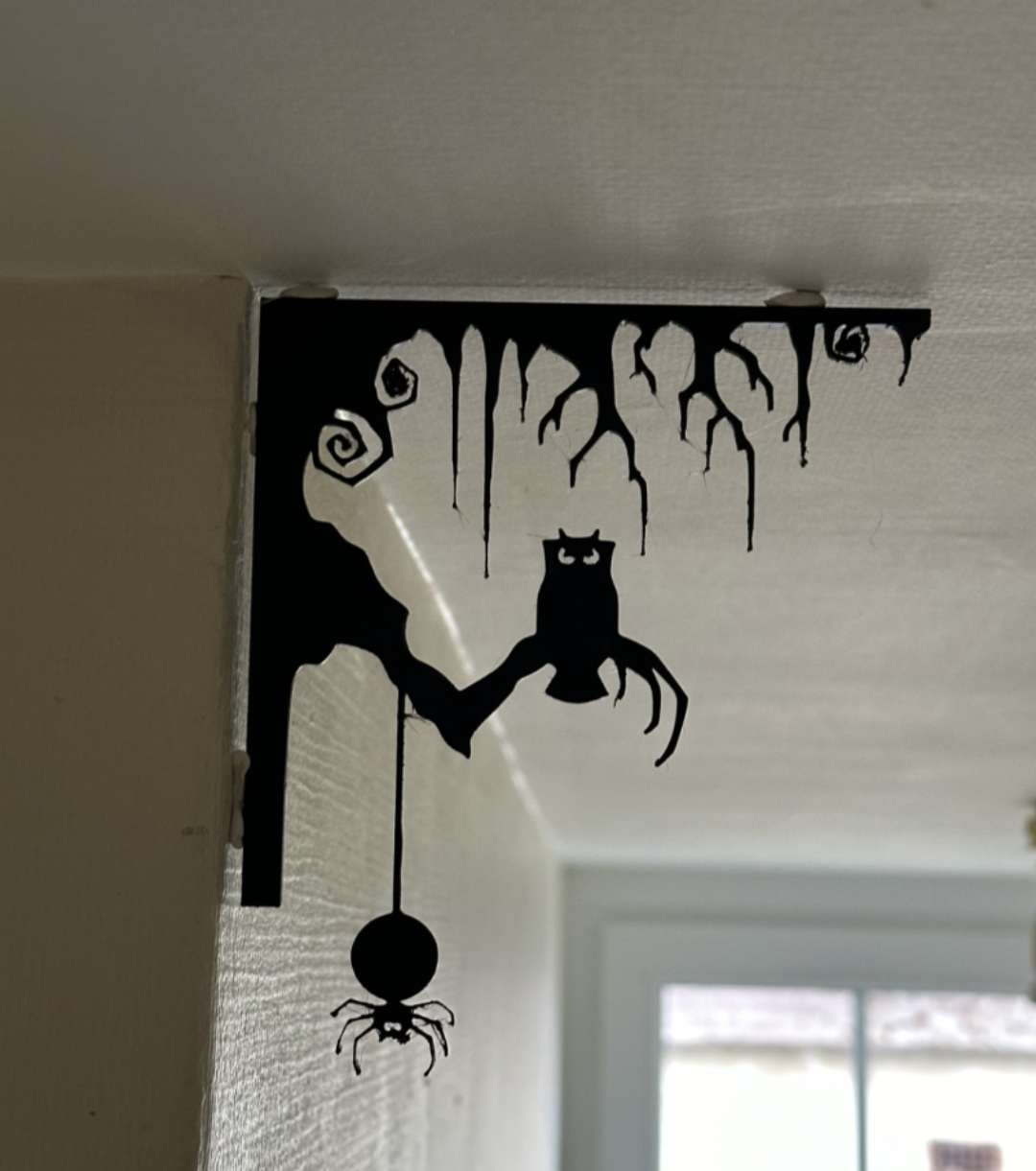 Black 3D printed Halloween corner decoration with dripping tree, owl, and spider installed in room corner, front view