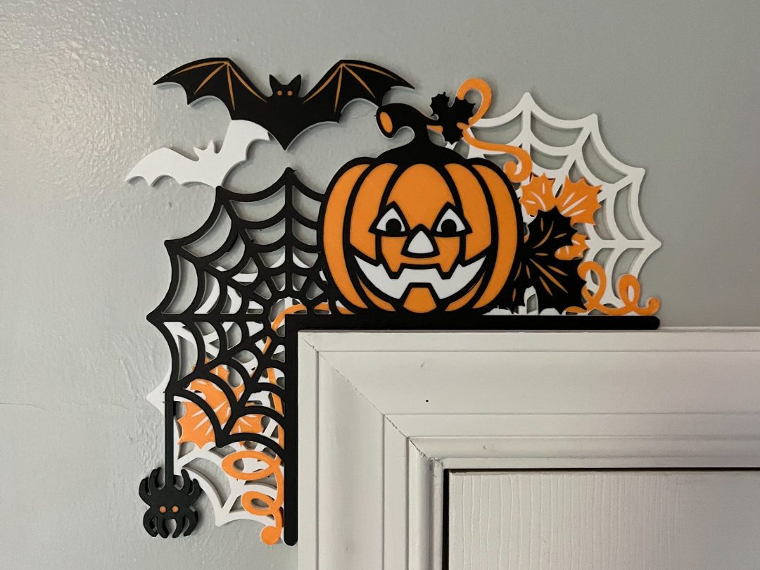 Multi-layer 3D printed Halloween door corner decoration with jack-o-lantern, spider webs, bats, and fall leaves in orange, black, and white